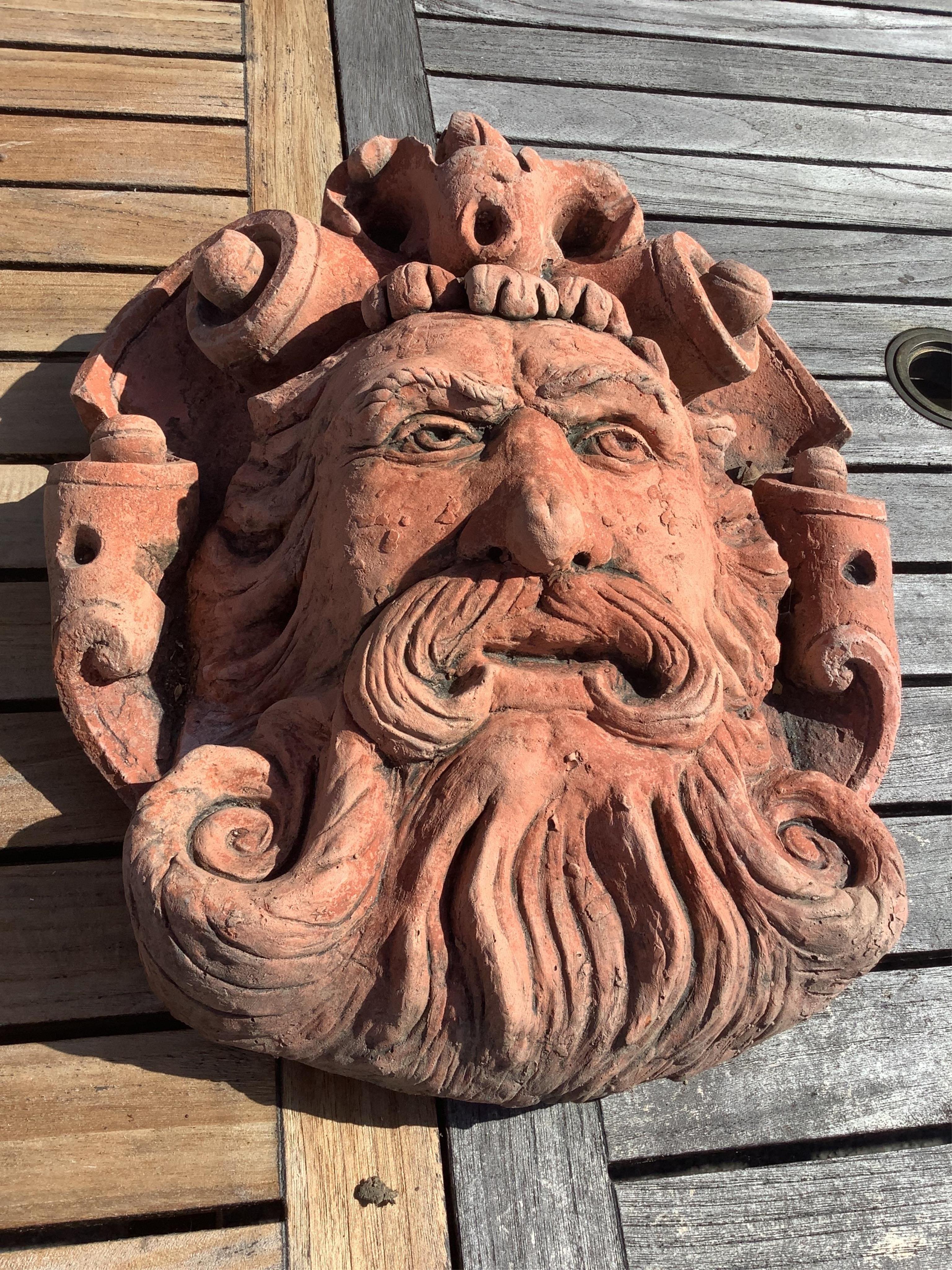 Three cast stone and terracotta garden wall mask appliqués, largest height 42cm